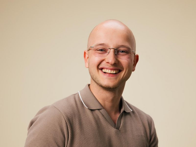 Lachender Hörakustik-Auszubildender mit Brille.