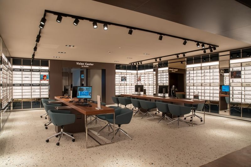 Beratungsbereich mit Holzschreibtischen und Essilor Vision Center im Flagshipstore Düsseldorf.