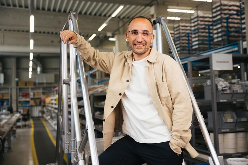 Lächelnder Apollo-Mitarbeiter mit Brille im Logistikbereich.