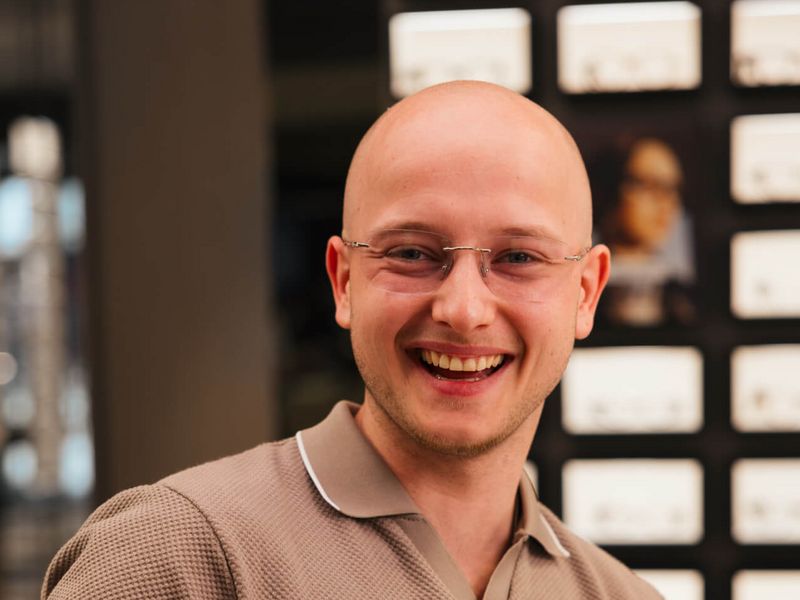 Lachender Apollo-Mitarbeiter mit randloser Brille.